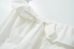 Détails de robe blanche avec tissu plissé et décoration de nœud élégante en gros plan
