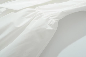Détail de la taille smockée et des plis élastiques sur un tissu tissé blanc pur