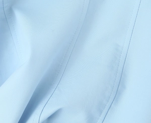 Detail aus hellblauem Webstoff mit hochwertigen Doppelnaht-Details und feiner Textur