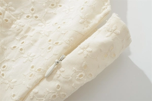 Détail de broderie anglaise élégante avec une fermeture éclair invisible sur une robe blanche