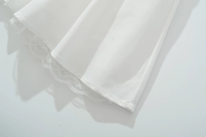 Gros plan sur l'ourlet en dentelle d'une robe blanche avec détails de couture