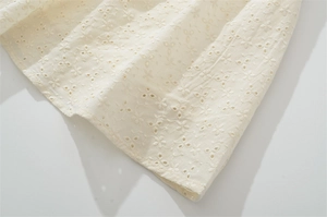 Détail du tissu brodé en dentelle blanc crème avec motifs floraux et texture coton