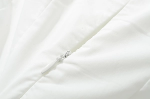 Gros plan d'une robe blanche montrant le tissu lisse et la fermeture éclair invisible de qualité