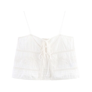 Detail of white camisole top featuring floral embroidery and delicate tie-front closures
