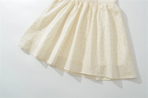 Détails de la broderie florale ajourée ivoire et de la taille élastique plissée