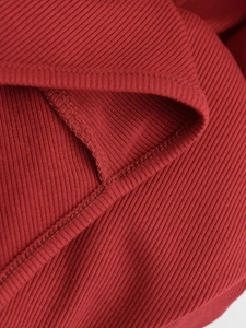 Détail macro du tissu en maille côtelée bordeaux avec coutures et ourlets haut de gamme