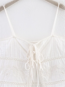 Detail of white bohemian camisole with floral embroidery and lace hollow-out design