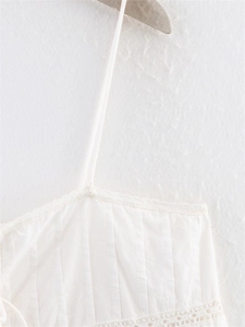 Detailed close-up of white camisole top with delicate lace edges and sheer cutout embroidery