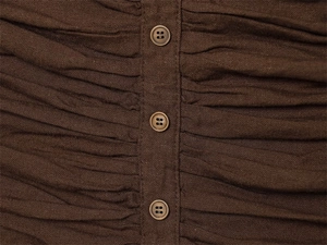 Close-up of deep brown pleated fabric with vertical button placket detailing