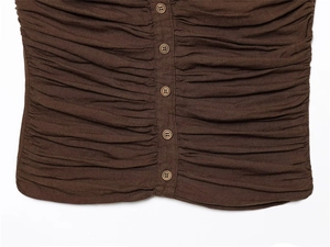 Macro view of dark brown ruched fabric with five vintage round buttons on the front