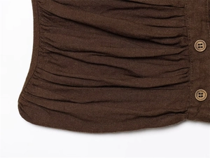 Macro detail of dark brown pleated fabric texture with vintage round button closure