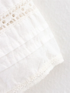 Detailed macro view of white cotton fabric with elegant lace edges and pleated layers