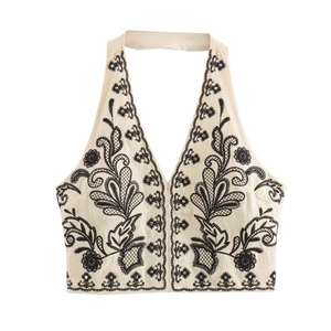 Embroidered halter top in off-white fabric with black floral patterns and metal studs