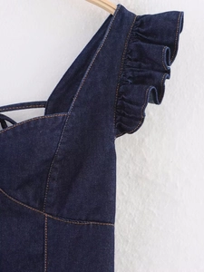 Detail of dark blue denim dress featuring ruffle straps and classic yellow topstitching