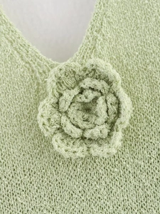 Détail du haut en tricot vert clair avec col en V et grande fleur au crochet 3D en relief