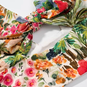 Détail d'un haut à imprimé floral tropical avec nœud décoratif et motif de feuilles de palmier