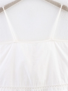 Close-up of white camisole top featuring delicate lace trim and thin spaghetti straps