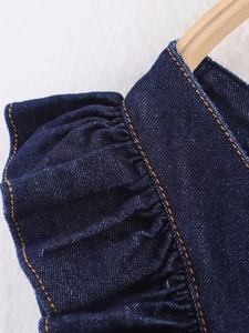 Detail of ruffle hem on dark blue denim skirt with contrast orange stitching