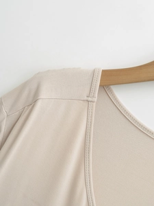 Close-up of beige knit top neckline with fine stitching and soft cotton texture