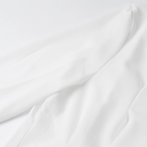 Detail shot of lightweight white chiffon fabric texture and sleeve seam on a long-sleeve shirt