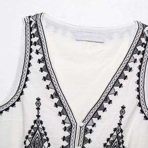 Detail of white cotton vest with black geometric embroidery and V-neckline button