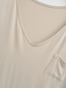Detail of V-neckline and decorative pocket on a beige knitted top for women