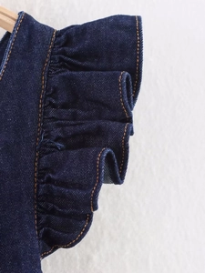 Detail of dark blue denim ruffle with orange contrast stitching and twill texture