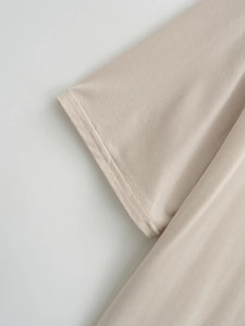 Detailed close-up of double-needle stitching and fabric texture on light beige short sleeve top