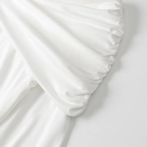Elegant white spring dress featuring sophisticated pleated texture and layered details
