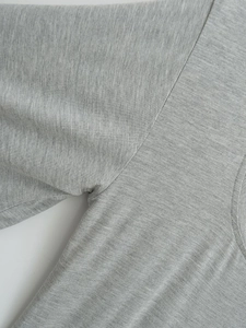 Close-up of heather grey knit fabric showing stitching detail on the shoulder and armhole
