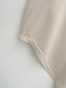 Detailed close-up of high-quality double-needle stitching on beige casual shirt sleeve