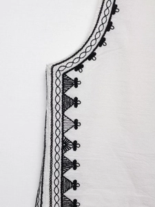 Detail of contrast embroidery on white cotton vest neckline with geometric patterns