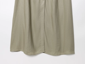 Detailed macro view of sage green linen midi skirt with silver buttons and seams
