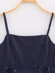 Detail of dark blue denim camisole featuring thin straps and two decorative bows