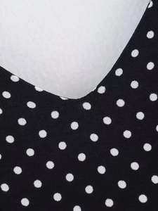 Detailed close-up of V-neckline featuring a classic black and white polka dot pattern fabric