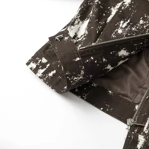 Detaillierte Makroansicht der dunkelbraunen Jacke mit weißem Spritzdruck und Metallreißverschluss
