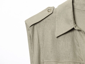 Macro detail of khaki linen shirt featuring epaulettes and metallic snap buttons