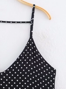 Detailed view of white polka dots on a black fabric with slim spaghetti straps