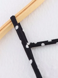 Detail of thin shoulder strap stitching and vintage polka dot fabric on a black dress