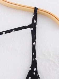 Macro detail of the fine shoulder straps and polka dot pattern on the black dress