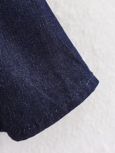 Detailed macro view of dark blue denim twill fabric with precise white topstitch detail