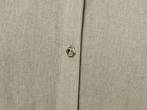 Detailed macro view of the breathable linen fabric texture and silver metal button