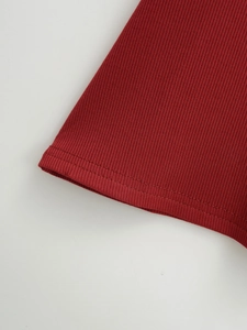 Dettaglio macro della maglia a coste rosso scuro con cuciture a doppio ago precise