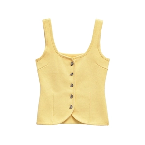 Close-up of light yellow knit vest top featuring ornate silver buttons and tight weave