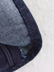 Macro detail of dark blue denim fabric with twill texture and seamless zipper closure