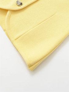 Macro detail of fine light yellow knit fabric and irregular silver metal button closure