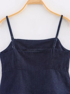 Detail of dark blue denim camisole with adjustable straps and flat neckline on a wooden hanger