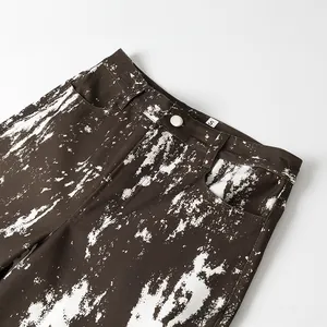 Dettaglio di pantaloni marroni con stampa tie-dye bianca ed etichetta taglia S in cotone