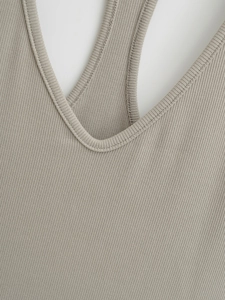 Detail of V-neck cut and racerback straps on khaki ribbed knit vest top