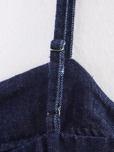 Detailed macro view of dark blue denim shoulder strap with silver metal adjuster buckle